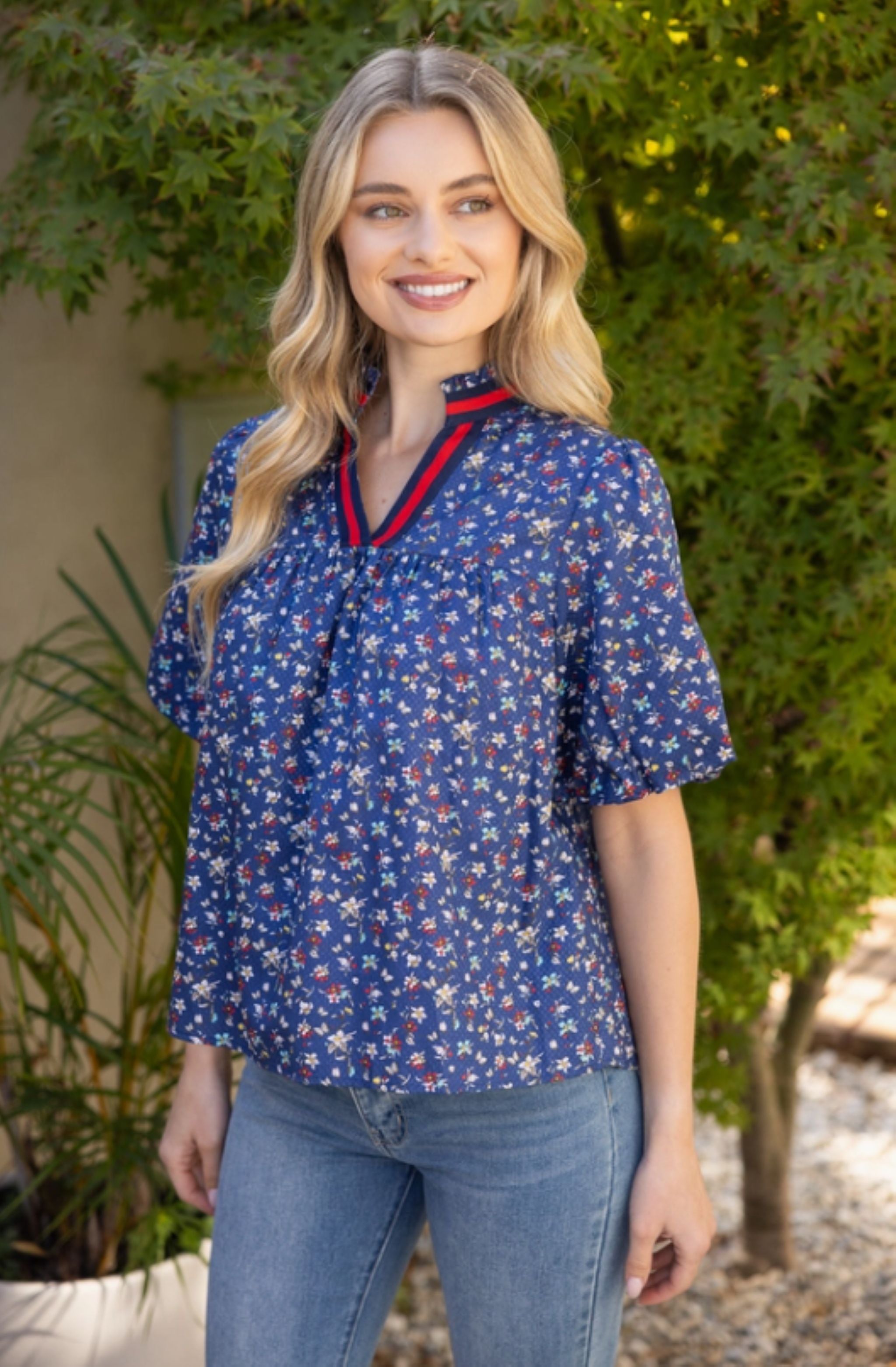 Woman wearing a blue floral blouse with a red collar