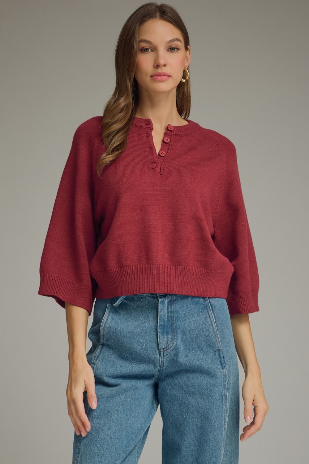 Bugundy knit sweater top with round neckline, button placket detail, three-quarter sleeves, and ribbed trim at cuffs and hem.