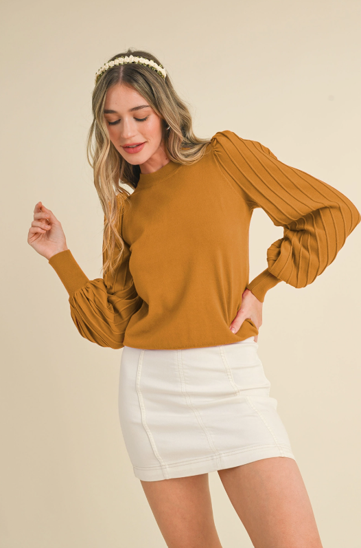 This knit sweater features elegant puff sleeves with structured ribbing, creating a polished, feminine look that easily transitions from everyday wear to special occasions.