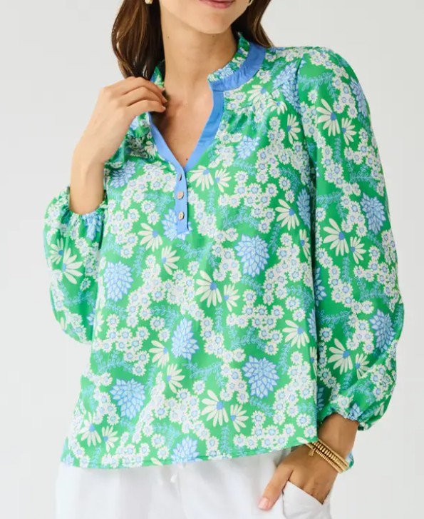 Woman wearing a green floral blouse with blue accents on a white background