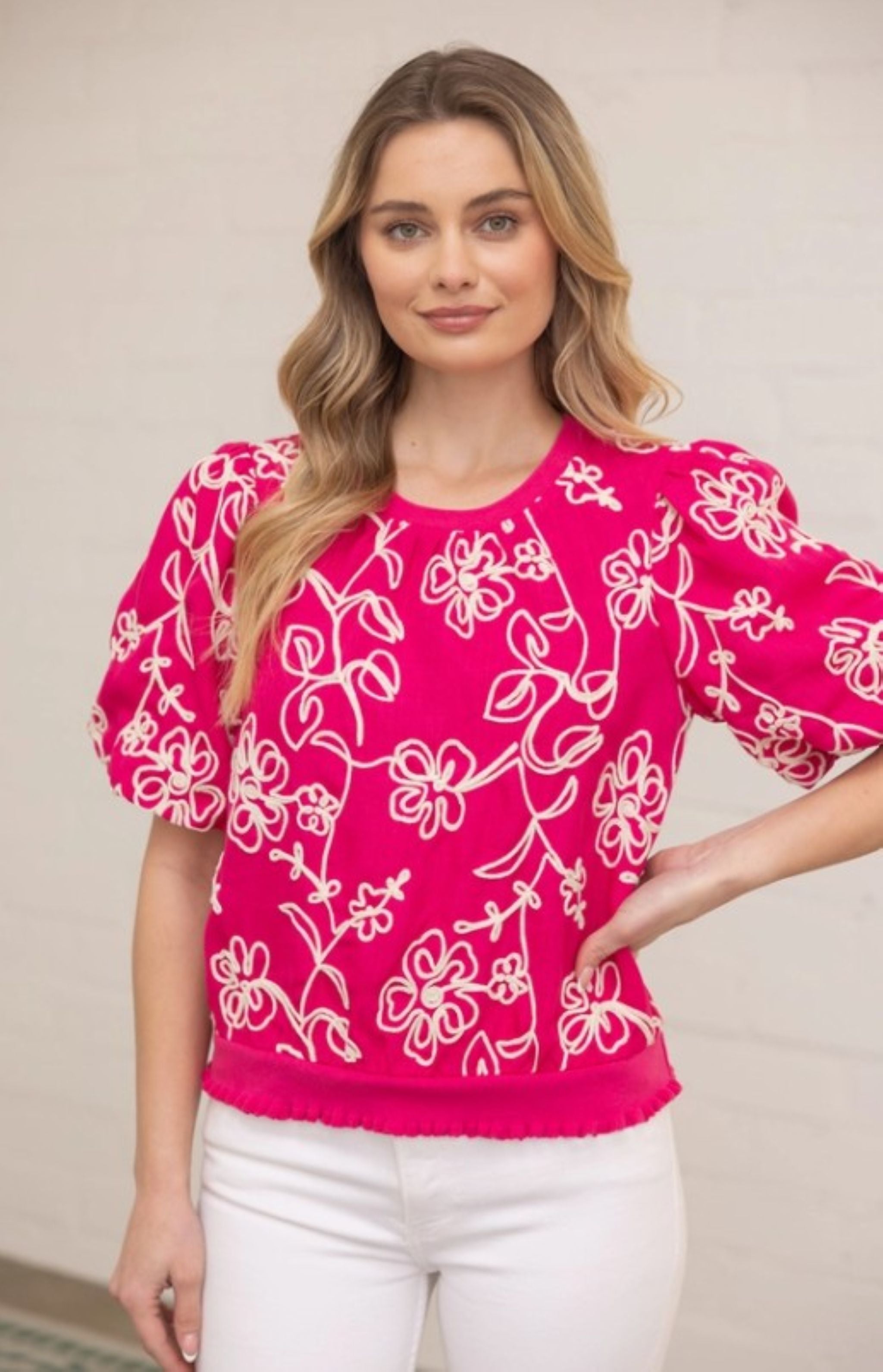 Woman wearing a bright pink blouse with white floral patterns