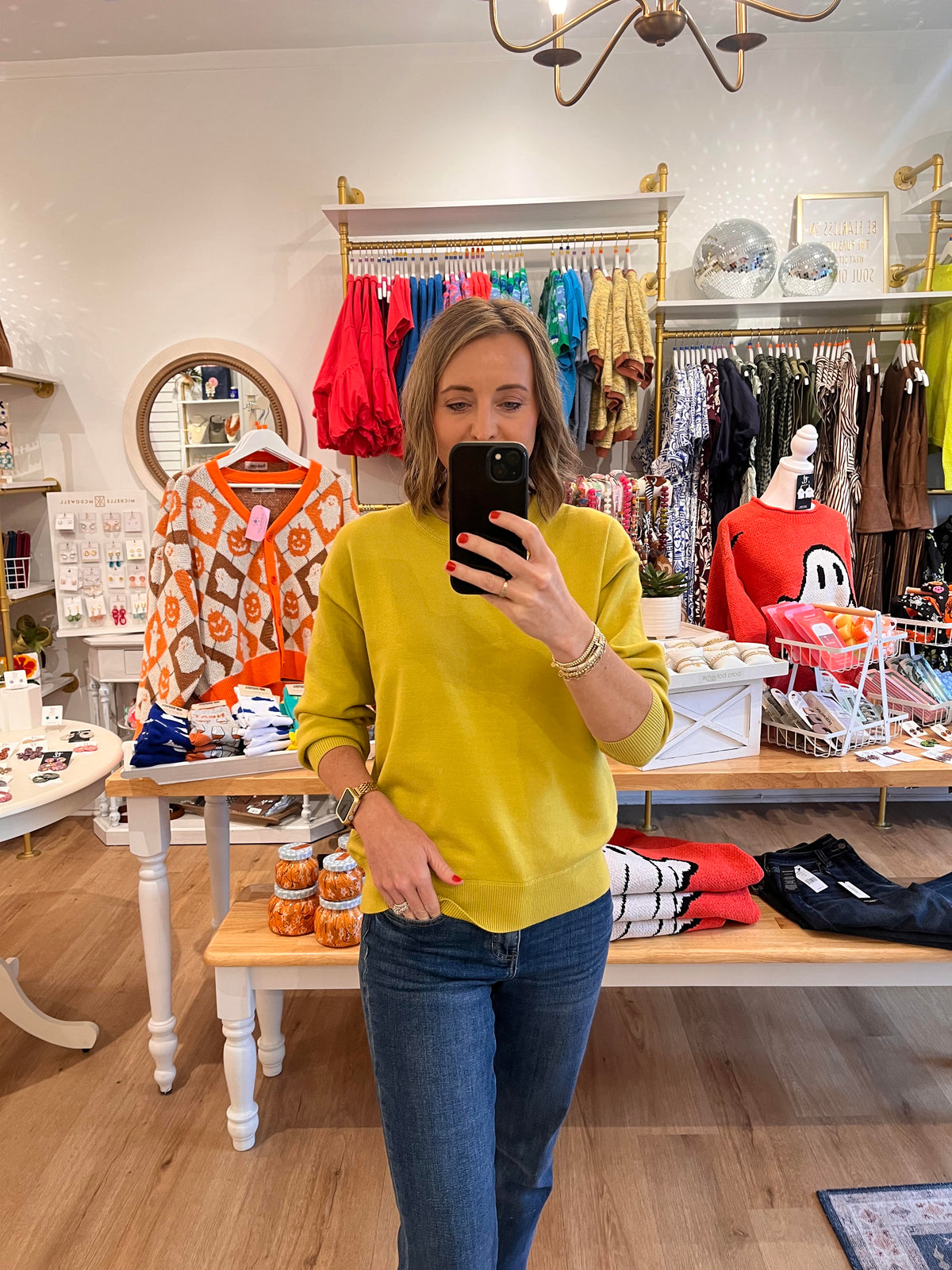 Woman wearing a lime green crewneck long sleeve top with ribbed cuffs and hem, styled with blue jeans.