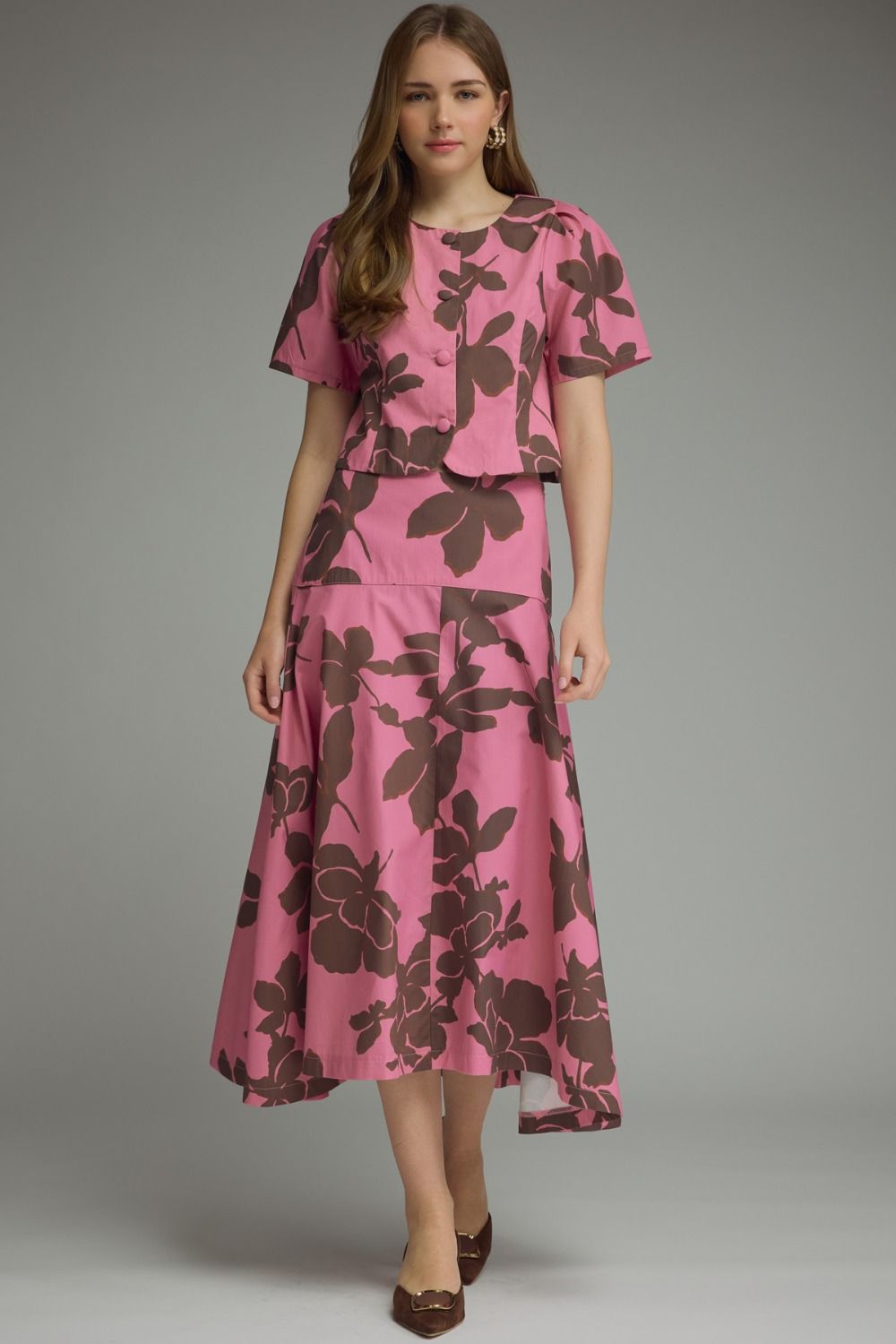 Vibrant pink and brown oversized floral print two-piece set with structured boxy short-sleeve top, button-front closure with self-covered buttons, and coordinating midi skirt with drop waist and side zip closure.