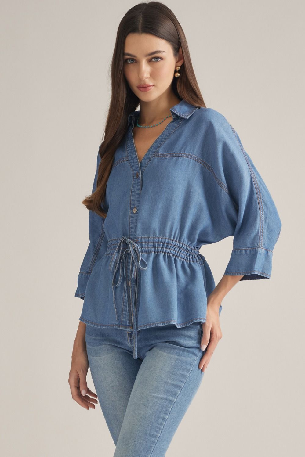 Medium wash Tencel denim top with drawstring waist, point collar, V-neckline, and dolman sleeves