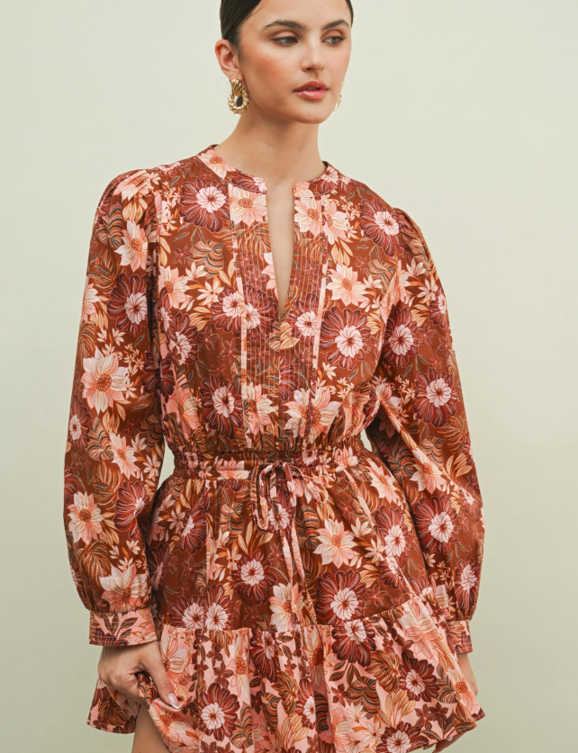 Chocolate brown floral mini dress with blush and cream botanical print, smocked drawstring waist, long sleeves, and tiered ruffle skirt