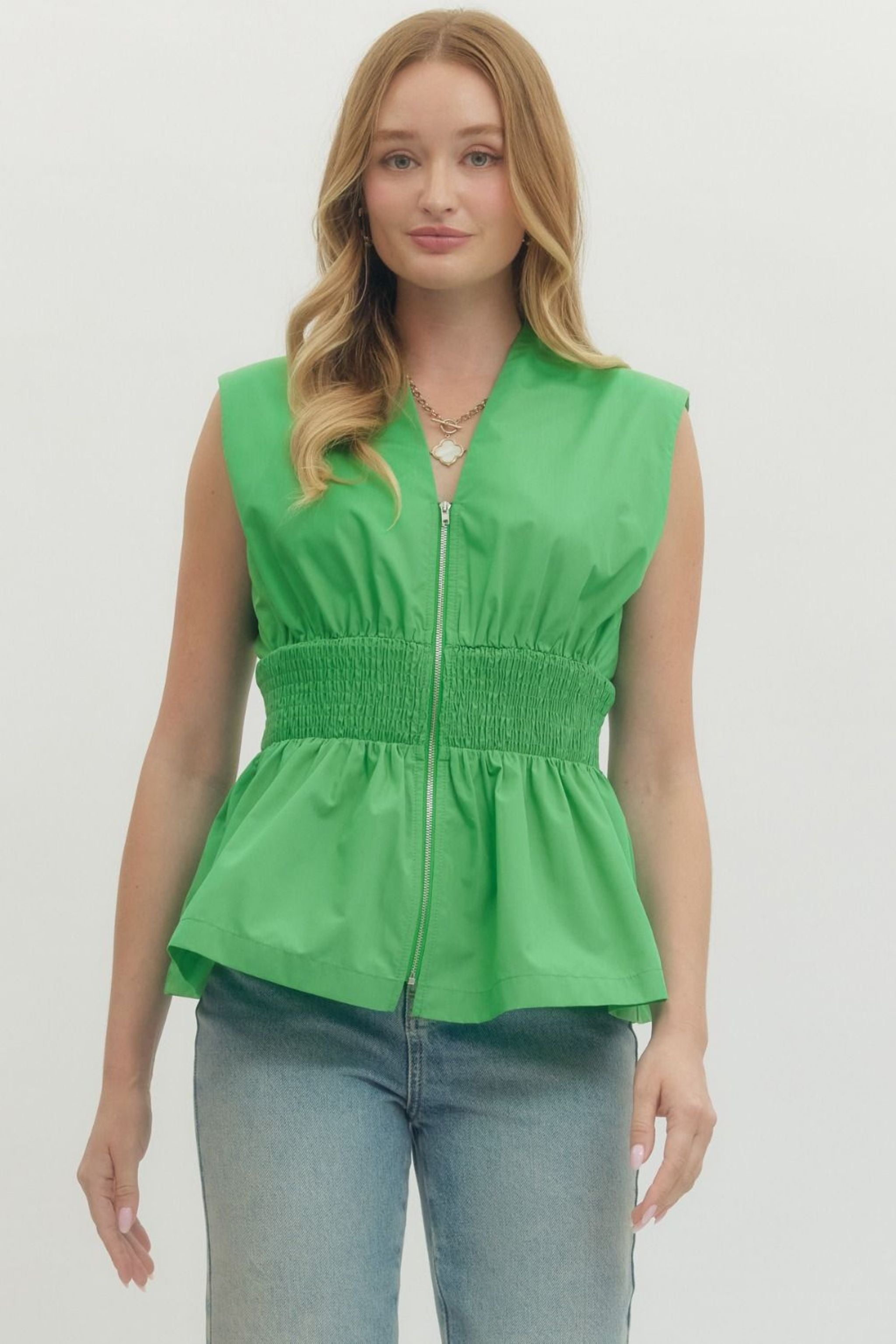 Woman wearing a green sleeveless top with a zipper 