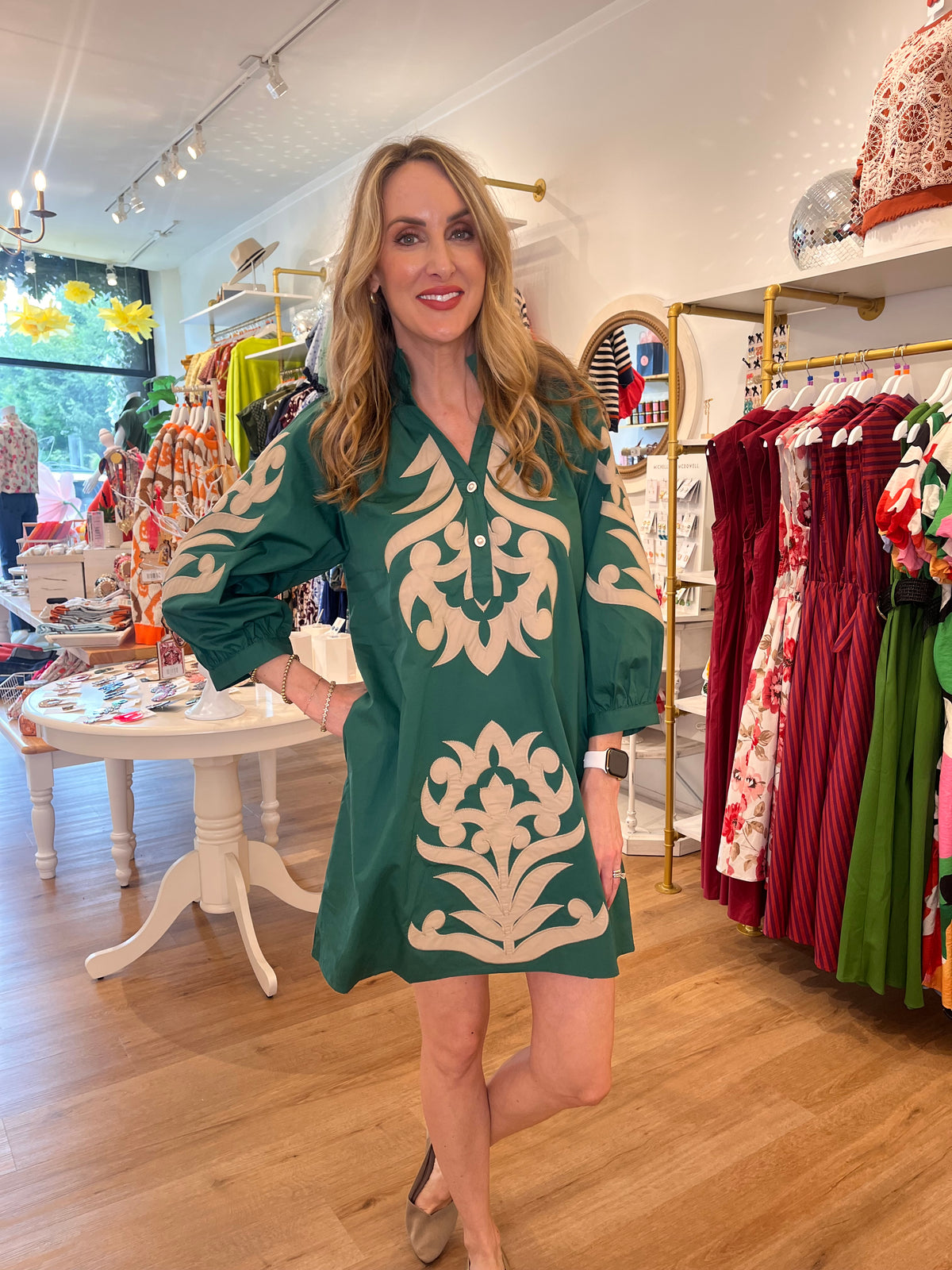 Make a statement in this hunter green mini dress, featuring intricate tan appliqué medallion motifs throughout the bodice, skirt, and balloon sleeves. 