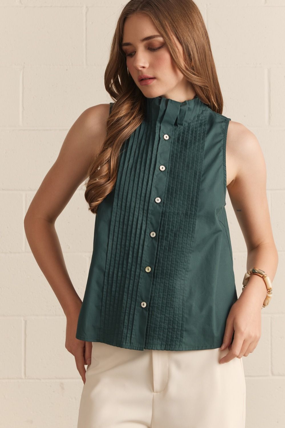 Hunter green sleeveless collared top with front pintuck pleating, button-front closure, and fitted silhouette hitting at the hip.