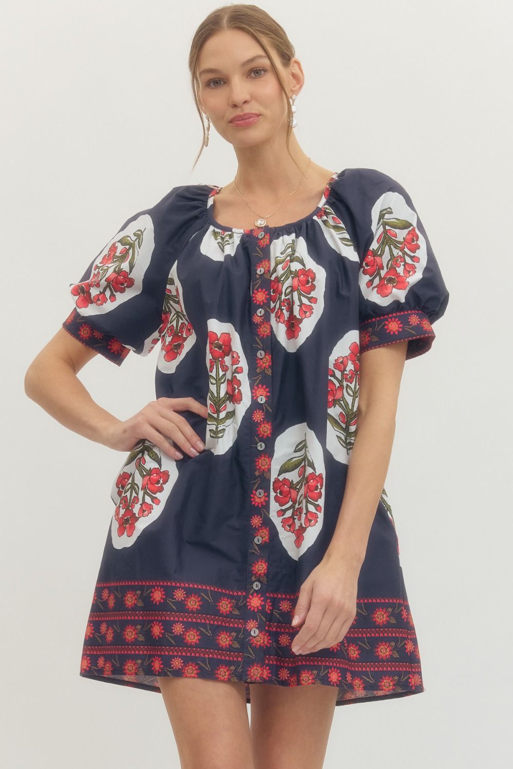 Woman wearing a navy dress with red and white floral patterns 