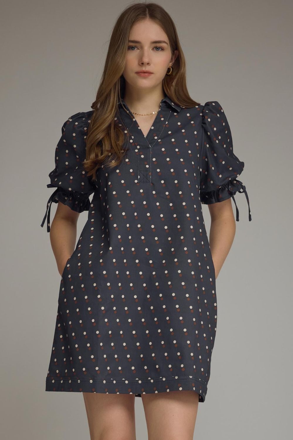 Denim mini dress with white polka dot print, short puff sleeves with drawstring tie detail, collared V-neck, back waist drawstring, side pockets, and lined construction.