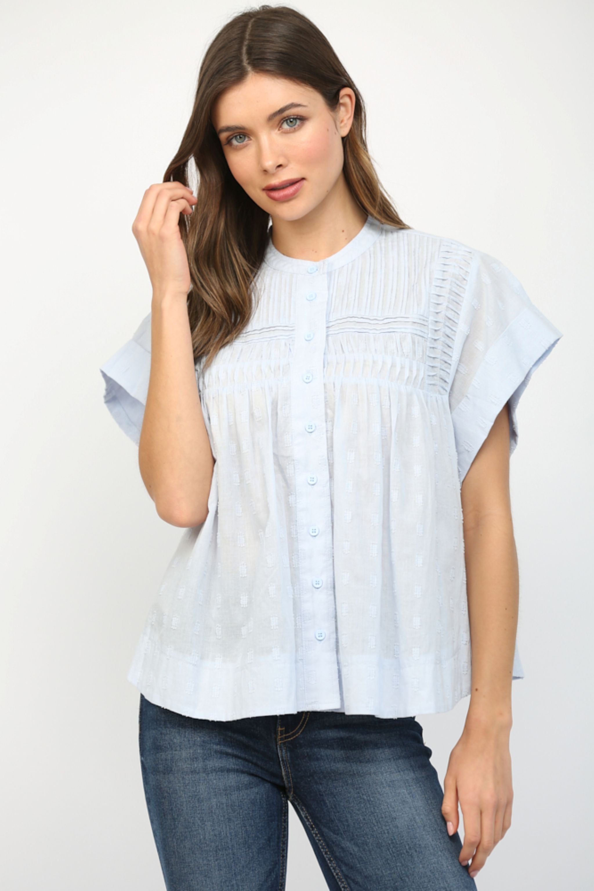 Woman wearing a light blue blouse and jeans on a white background