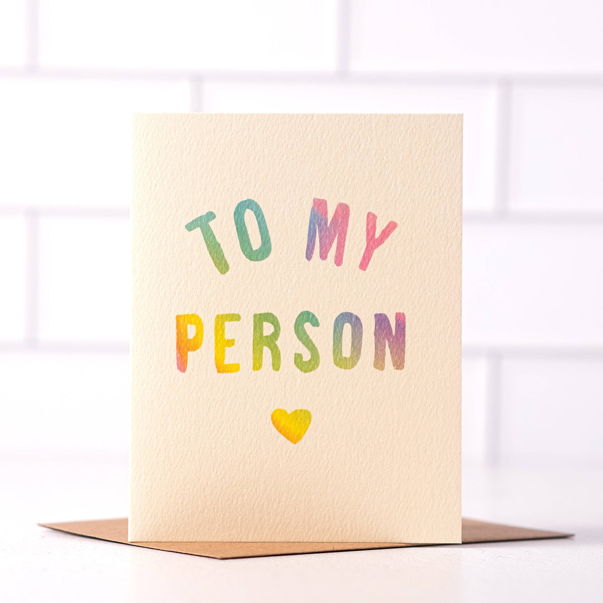 Cream “To My Person” greeting card with multicolored lettering and a yellow heart, shown with a kraft envelope.