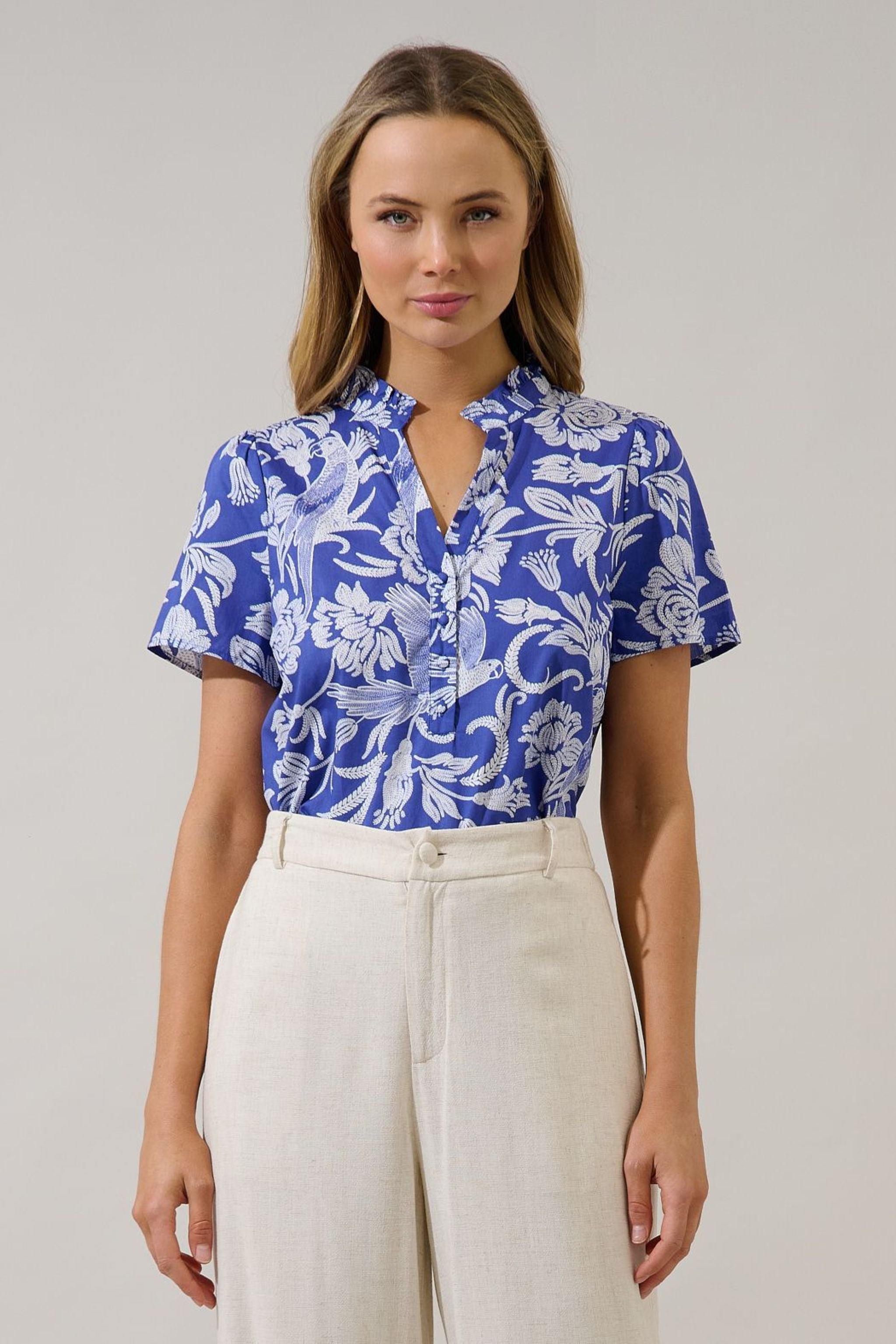 Woman wearing a blue floral blouse and white pants